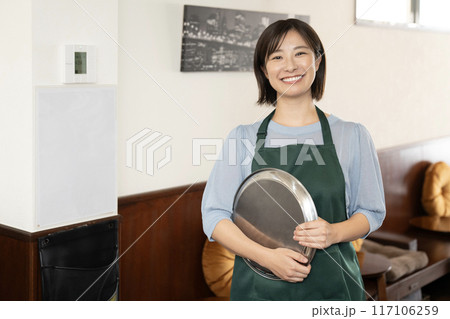 銀色のお盆を持って微笑むカフェの女性スタッフ 銀色のお盆を持って微笑むカフェの女性スタッフ 117106259