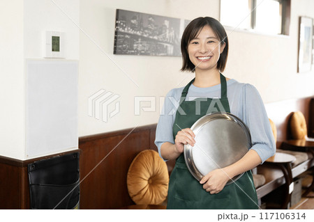 銀色のお盆を持って微笑むカフェの女性スタッフ 銀色のお盆を持って微笑むカフェの女性スタッフ 117106314