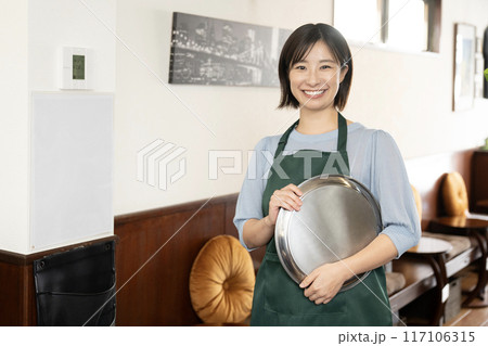 銀色のお盆を持って微笑むカフェの女性スタッフ 銀色のお盆を持って微笑むカフェの女性スタッフ 117106315