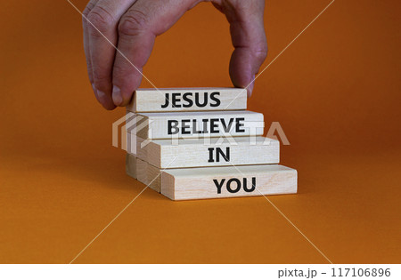 Jesus believe in you symbol. Concept words 'Jesus believe in you' on wooden blocks on a beautiful orange background. Businessman hand. Business, religion and Jesus believe in you concept. 117106896