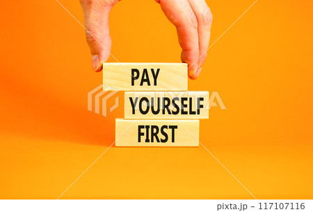 Pay yourself first symbol. Concept words Pay yourself first on beautiful wooden blocks. Beautiful orange table orange background. Businessman hand. Business and pay yourself first concept. Copy space. 117107116