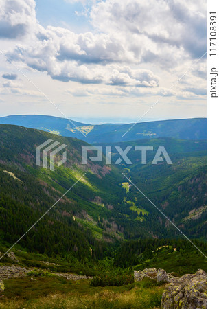 Beautiful panoramic view of green mountain valley with rolling hills and dense forests under cloudy sky. Travel tourism and hiking concept Beautiful panoramic view of green mountain valley with rolling hills and dense forests under cloudy sky. Travel tourism and hiking concept 117108391