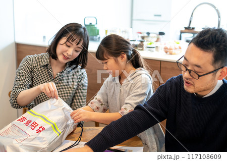 非常持ち出しバッグに防災用品をパッキングしている家族 117108609
