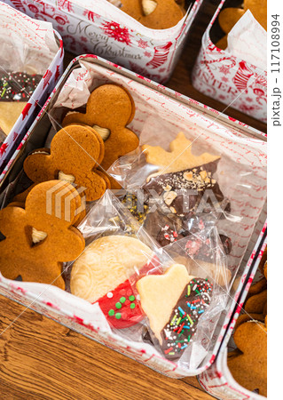 Lovingly homemade gingerbread and sugar cookies, half-dipped in rich chocolate, nestled in decorative Christmas tin boxes perfect for seasonal gifting. Lovingly homemade gingerbread and sugar cookies, half-dipped in rich chocolate, nestled in decorative Christmas tin boxes perfect for seasonal gifting. 117108994
