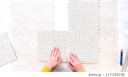 Flat lay. In the process of mounting peel and stick mosaic tiles onto a foam board, perfect for enhancing a food photography studio's aesthetic. 117109106