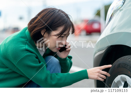 車のトラブルで電話する女性 自動車事故で困る女性 車のトラブルで電話する女性 自動車事故で困る女性 117109133