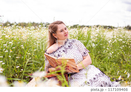 Beautiful woman in the field with flowers. 117109408