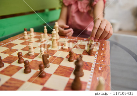 Close-up of child playing chess outdoors on a sunny day 117109433