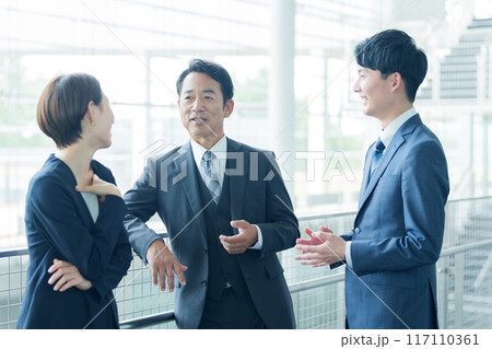 オフィスの廊下で雑談をするビジネスパーソン 117110361