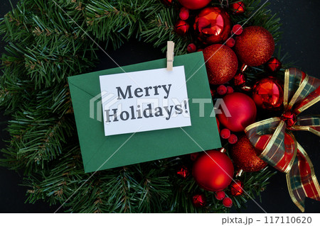 MERRY HOLIDAYS text on postcard with green envelope on handmade Christmas wreath. Zero waste eco-friendly Christmas. Sustainable greeting card 117110620