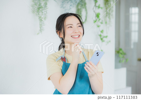 スマホを見るエプロンの女性 スマホを見るエプロンの女性 117111383