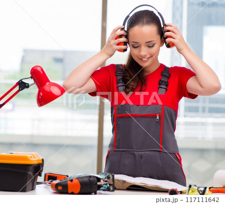 Young woman in coveralls doing repairs 117111642