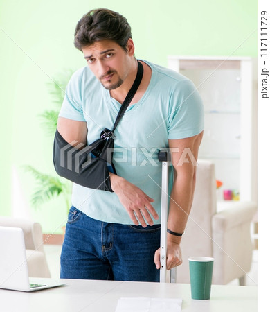 Injured man with crutches sitting at home Injured man with crutches sitting at home 117111729