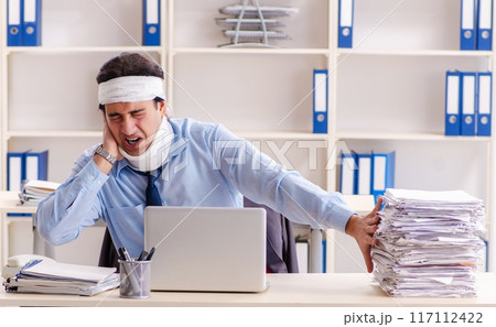 Young injured male employee working in the office Young injured male employee working in the office 117112422