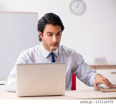 Young handsome financial speciaist in front of white board 117112478