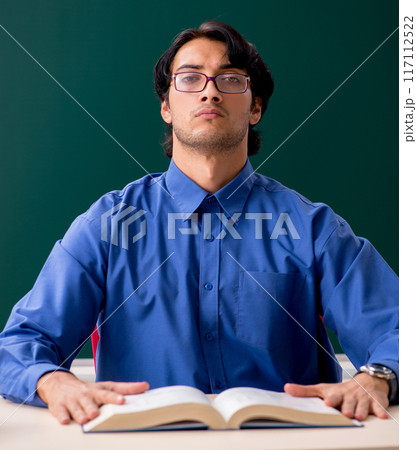 Young male teacher in front of chalkboard 117112522