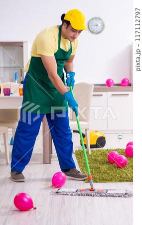 Young male contractor doing housework after party 117112797