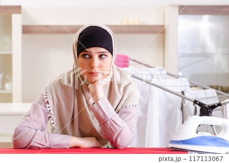 Woman in hijab doing clothing ironing at home 117113067