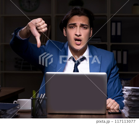 Young male employee working night in the office 117113077
