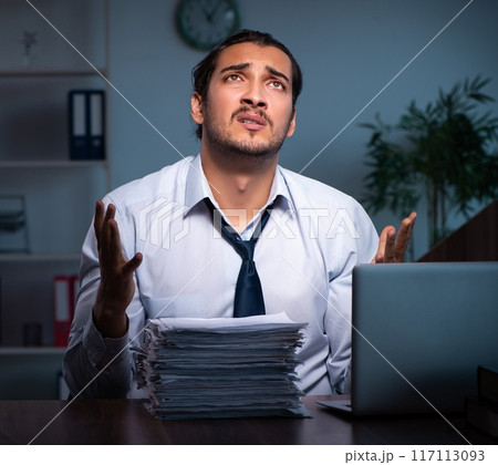 Young male employee working in the office night time 117113093