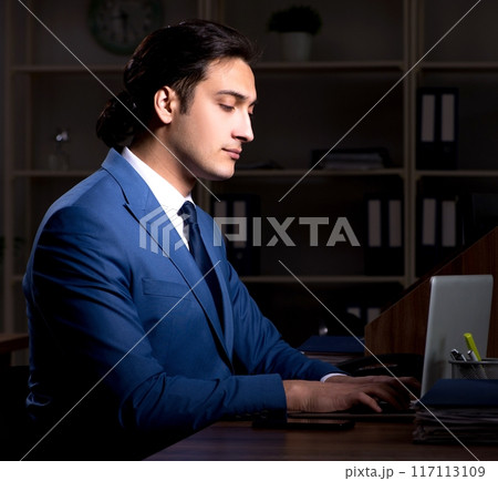Young male employee working night in the office Young male employee working night in the office 117113109
