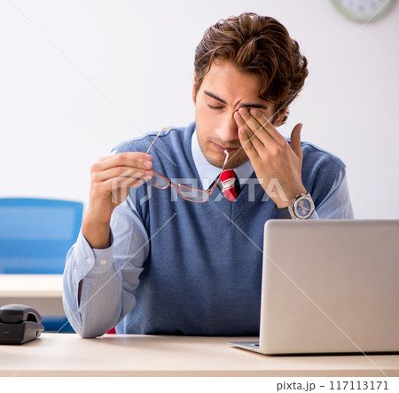 Young handsome employee unhappy with excessive work Young handsome employee unhappy with excessive work 117113171