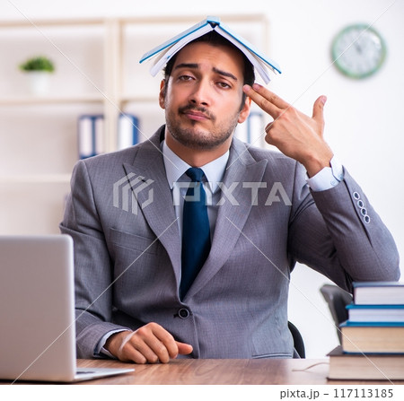 Young male businessman reading books at workplace Young male businessman reading books at workplace 117113185