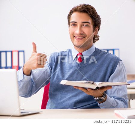Young handsome employee working in the office 117113223