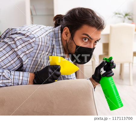 Young male contractor cleaning the house in coronavirus concept Young male contractor cleaning the house in coronavirus concept 117113700
