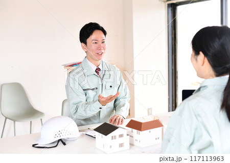 建設模型を使い会議をする作業服を着た男女 117113963