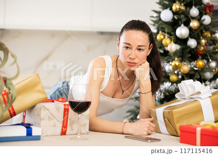 pensive young girl stands among New Year s gifts 117115416