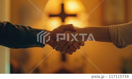 Two people of different faiths shaking hands in front of a glowing cross. 117115739