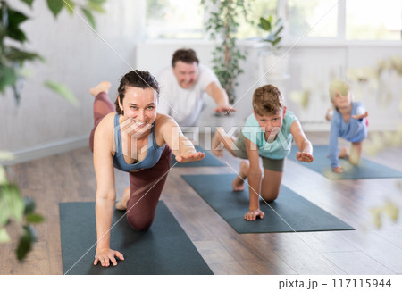 Family with two children doing yoga in studio 117115944
