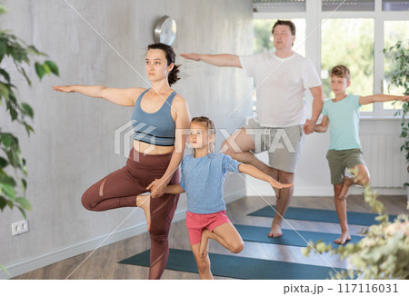 Harmonious family members practicing tree pose in pairs 117116031