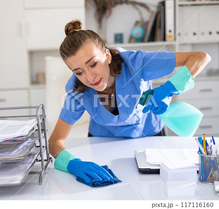 Female cleaning service worker wiping working table in office 117116160