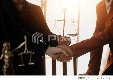 Lawyer shaking hands with a client making about documents, contracts, agreements, cooperation agreements with a female client at the lawyer's desk and a hammer at the table. 117117095