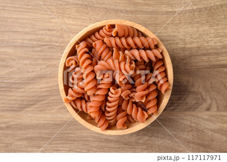 Raw fusilli pasta in bowl on wooden background, Table top view Raw fusilli pasta in bowl on wooden background, Table top view 117117971