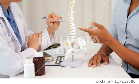 Orthopedists holding digital tablet and pointing at model. Concept of osteoporosis, back pain, lumbar, chiropractic and health. Orthopedists holding digital tablet and pointing at model. Concept of osteoporosis, back pain, lumbar, chiropractic and health. 117118586