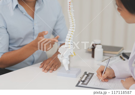 Orthopedists holding digital tablet and pointing at model. Concept of osteoporosis, back pain, lumbar, chiropractic and health. Orthopedists holding digital tablet and pointing at model. Concept of osteoporosis, back pain, lumbar, chiropractic and health. 117118587