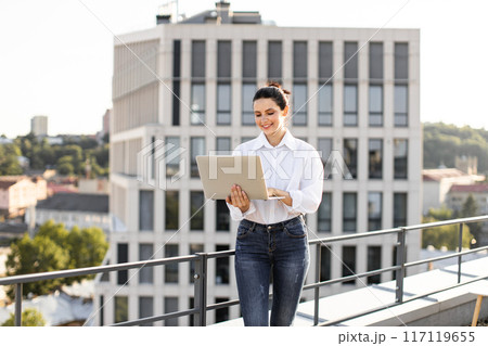 Young woman working on rooftop with laptop in urban setting Young woman working on rooftop with laptop in urban setting 117119655