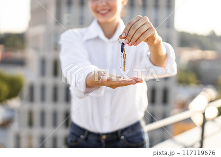 Woman holding house keys in urban setting Woman holding house keys in urban setting 117119676