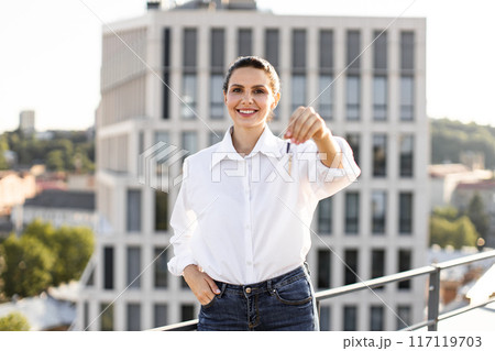 Happy woman showing keys to new apartment on rooftop 117119703