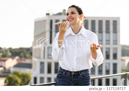 Woman talking on smartphone outdoors with office buildings in background 117119727