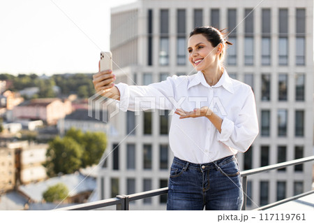 Woman taking selfie on balcony in urban environment Woman taking selfie on balcony in urban environment 117119761