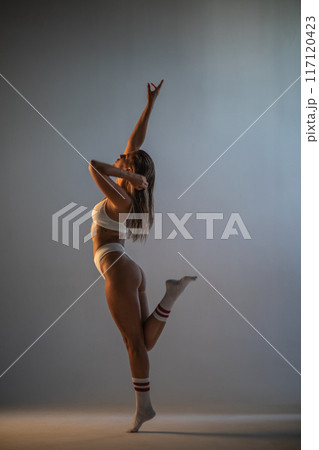 Beautiful athletic girl in socks and underwear posing in a photo studio. Dramatic light. Vertical photographs. 117120423