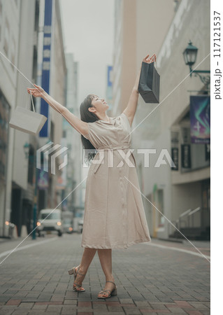 都会の街角で、買い物袋を手に心躍る女性 都会の街角で、買い物袋を手に心躍る女性 117121537