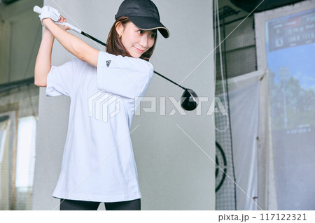 室内ゴルフ練習場で練習をする女性 117122321