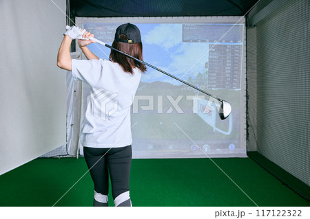 室内ゴルフ練習場で練習をする女性 117122322
