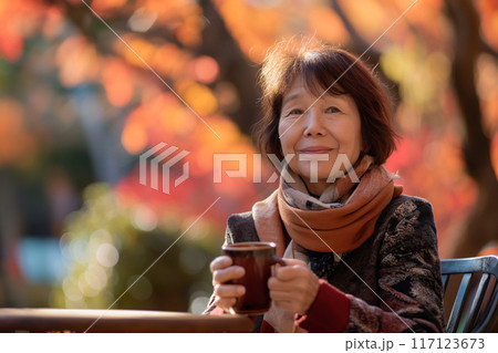 秋のカフェでコーヒーを飲むシニア女性 117123673