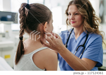 Doctor examining lymp nodes on neck of the young girl. Palpation of lymph nodes. Concept of school entry medical exam. 117124361